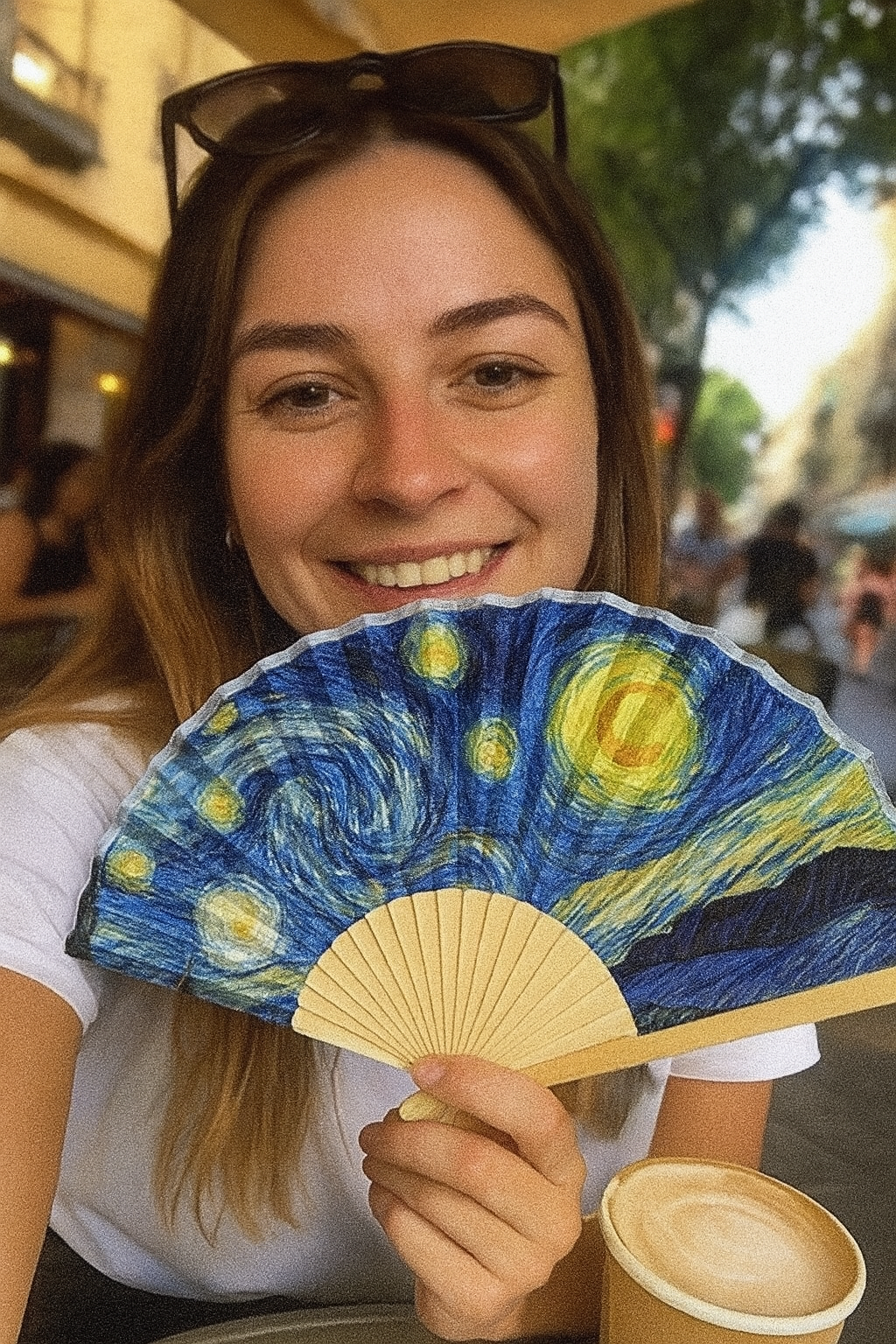 Woman holding a fan with 'Starry Night' design outdoors