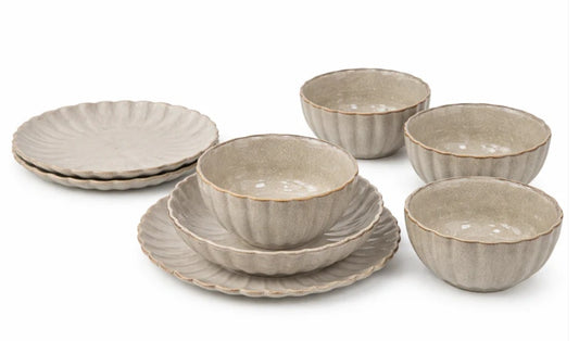 A set of ceramic tableware in a warm beige-gray glaze, including scalloped plates and matching bowls, arranged on a clean white background.